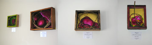Wide view of four framed art boxes featuring bright pink hearts hanging on wall