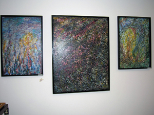 Three framed colorful abstract paintings hanging on wall