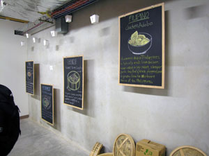 Photo of wall with four menu like boards and several Chinese take out boxes hanging from ceiling